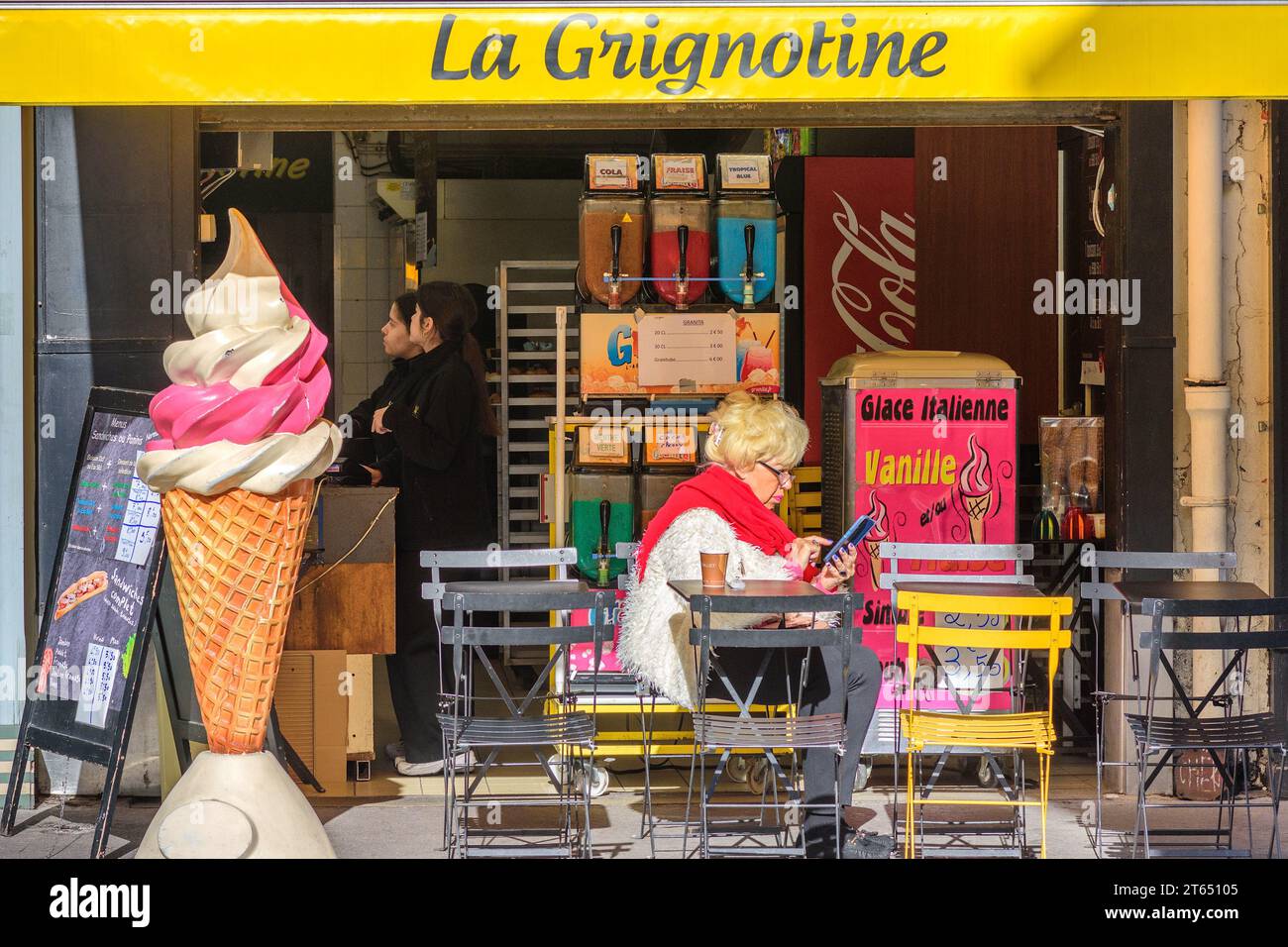 Femme assise à la terrasse du café vérifiant smartphone - Tours, Indre-et-Loire (37), France. Banque D'Images