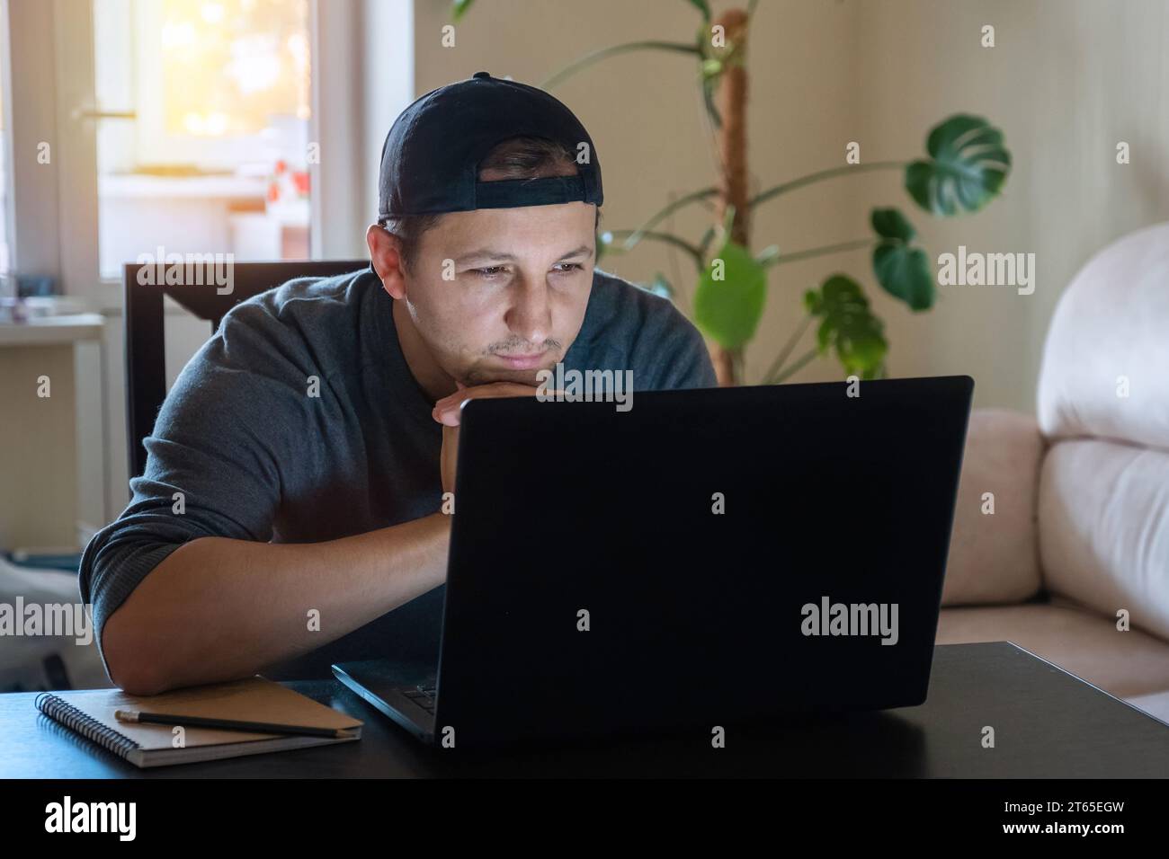 Un jeune homme travaille avec un ordinateur à distance de la maison. Travailler à domicile pendant l'isolement dû à une épidémie de virus Banque D'Images