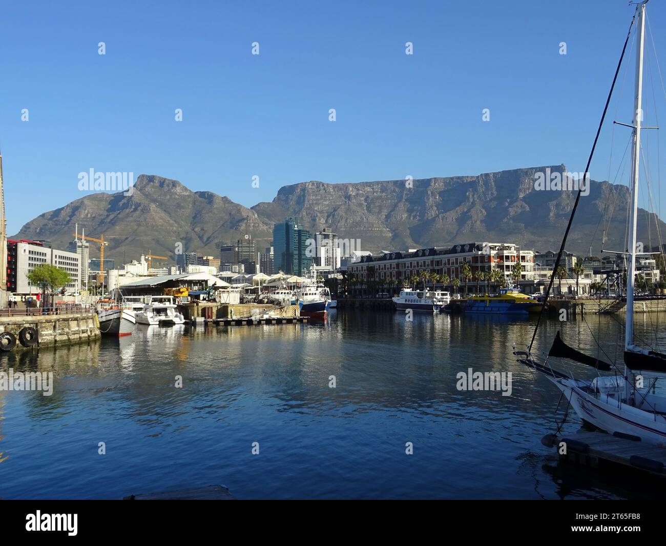 Bateaux et yachts amarrés au port de Victoria and Alfred Waterfront avec la montagne de la Table dominant l'horizon du centre-ville du Cap Banque D'Images
