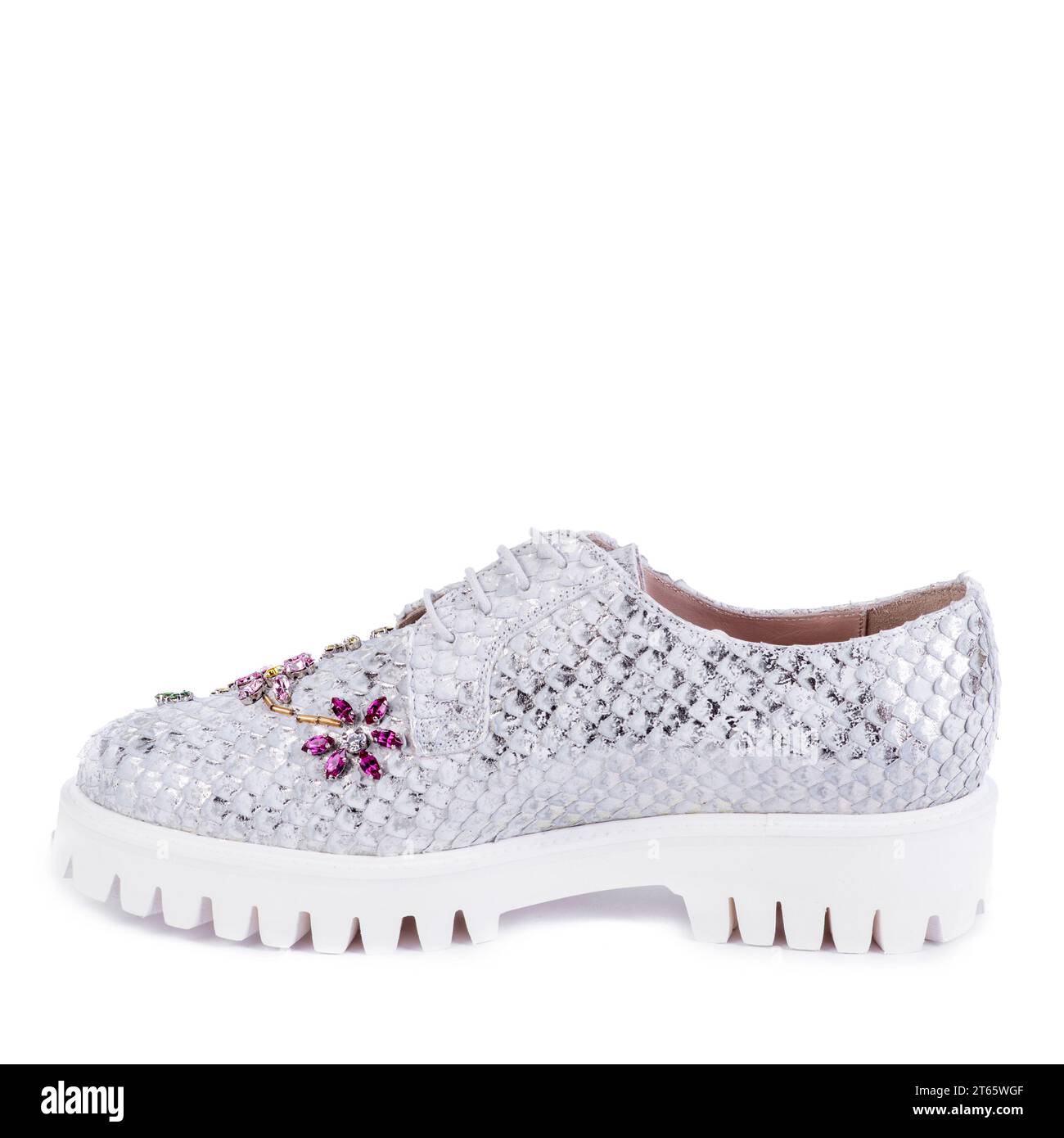 Chaussure audacieuse pour femme en matériau argenté, imitant les écailles de poisson, avec une semelle côtelée blanche décorée d'un ornement floral en strass multicolore Banque D'Images
