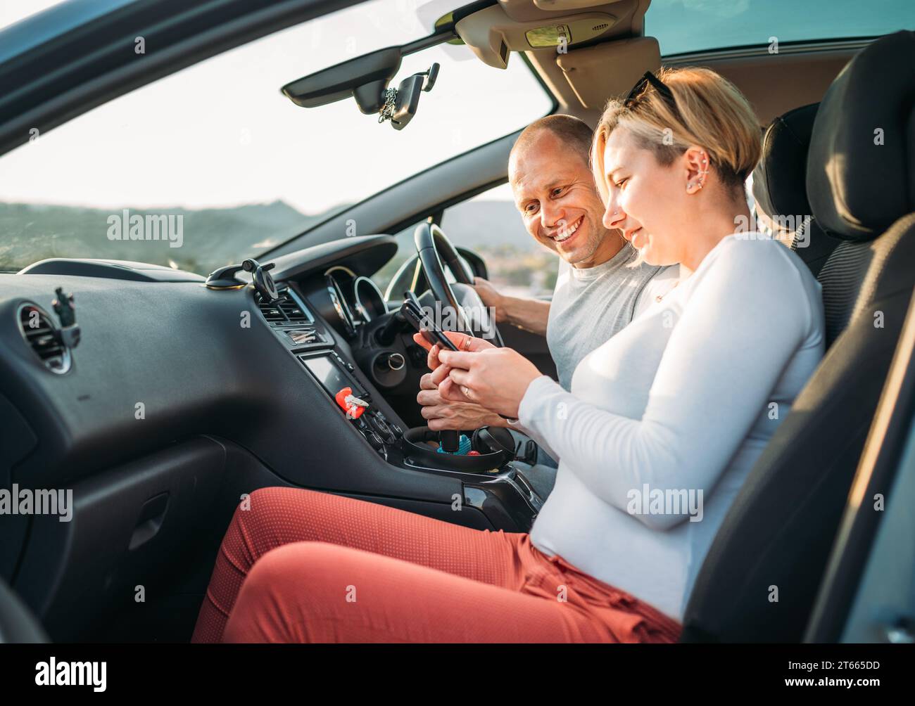 Heureux souriant deux jeunes adultes couple utilisant la navigation smartphone à l'intérieur de la voiture pendant auto jorney.They rient pendant le voyage sur la route. Famille, couples re Banque D'Images