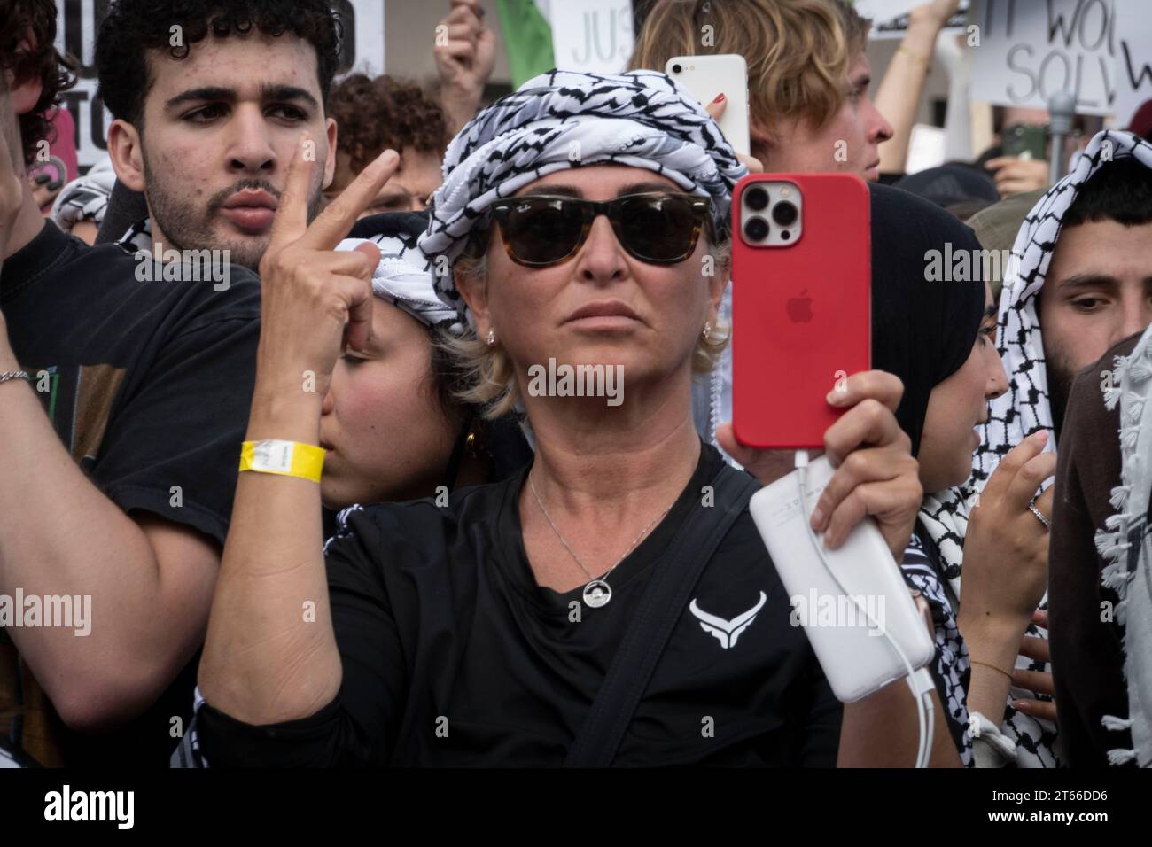 4 novembre 2023, Washington, District de Columbia, États-Unis: au cœur du rassemblement, des individus sont photographiés exprimant leur solidarité avec la cause pro-palestinienne au Freedom Plaza à Washington, DC. Une femme du centre, ornée d'un keffieh, se concentre attentivement sur son téléphone, capturant peut-être le moment ou diffusant l'événement en direct à un public plus large. Les diverses expressions et les regards focalisés de ceux qui l'entourent illustrent le sentiment partagé et l'engagement actif des manifestants. La scène résume la résonance émotionnelle et l'effort collectif des participants advocatin Banque D'Images