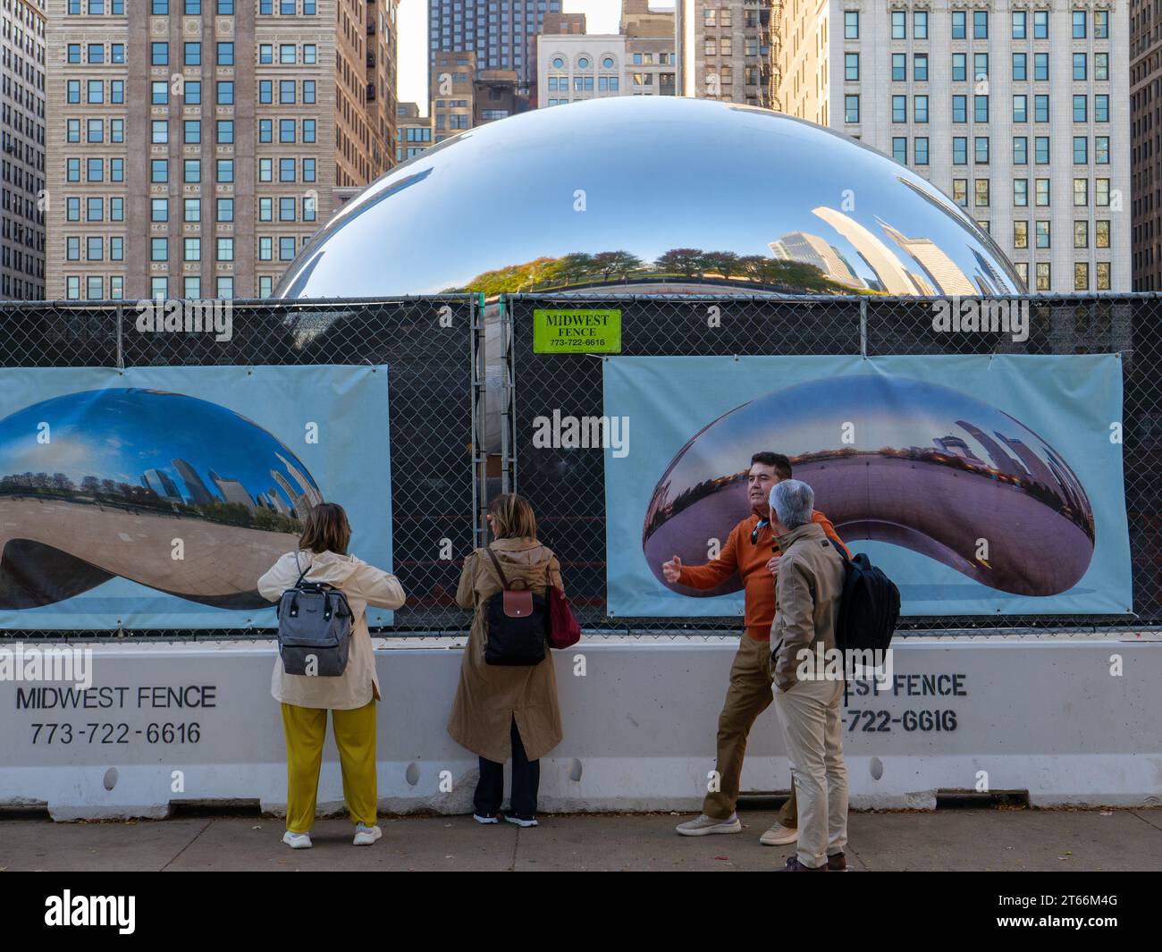 Les touristes essaient de voir Cloud Gate aka The Bean à travers une clôture de construction. Le plaza est fermé pour rénovation jusqu'au printemps 2024. Chicago, Illinois. Banque D'Images