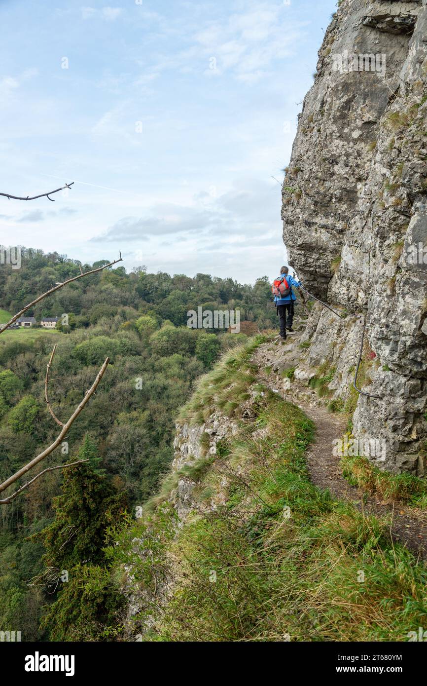 Un marcheur sur Giddy Edge sur la colline High Tor est un chemin sinueux exposé étroit le long du bord de la falaise avec Matlock Bath ci-dessous Banque D'Images