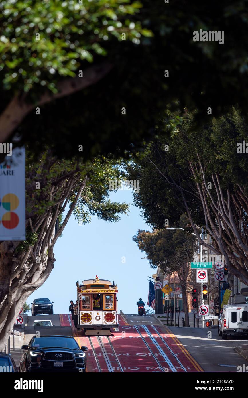 San Francisco, Californie, États-Unis - 24 avril 2023 : téléphérique sur la route asphaltée colorée sur la rue vallonnée avec des panneaux de signalisation routière passant sous g Banque D'Images