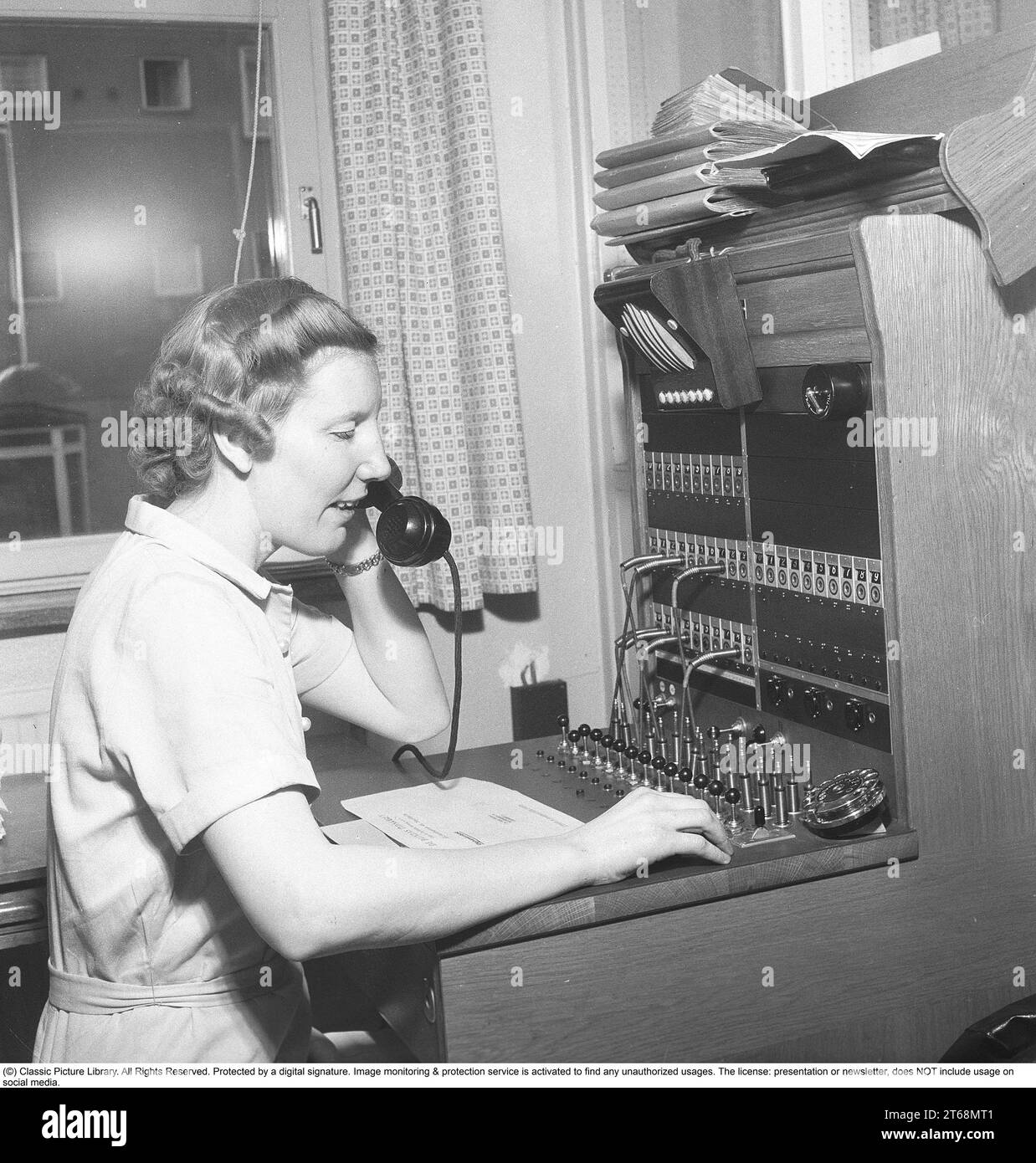 Une opératrice qui travaille dans le standard de l'entreprise. Elle connecte les appels entrants et sortants à la bonne personne en utilisant des cordons pour les téléphones respectifs dans un standard téléphonique. Suède 1954 Kristoffersson ref BO71-9 Banque D'Images