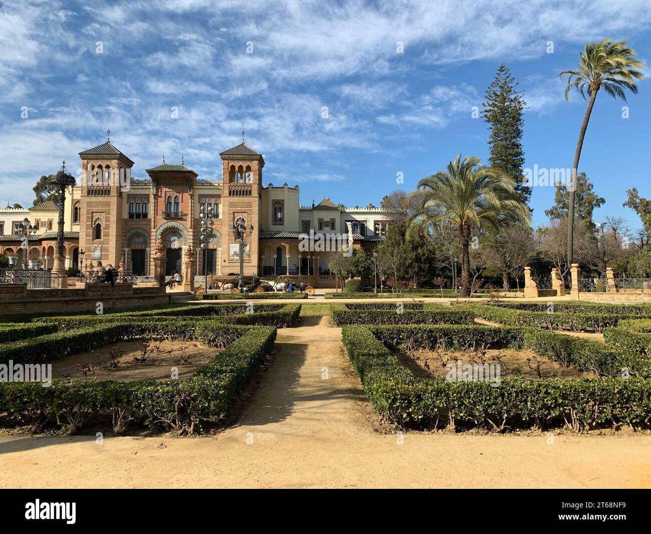 Un paysage extérieur avec un jardin élégant avec de petites haies de boîte et de l'herbe manucurée devant une structure grandiose en briques rouges Banque D'Images