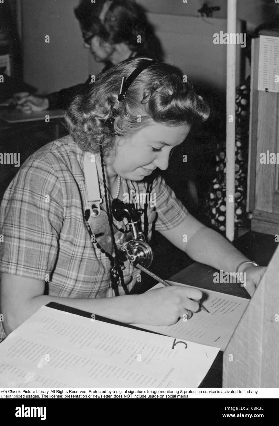 La téléphonie dans les années 1940 Femme travaillant à un standard téléphonique comme opérateur. Un système de communication téléphonique qui était actionné manuellement où les appels entrants étaient renvoyés et réacheminés vers un autre numéro de téléphone par l'opérateur, en l'occurrence localement dans l'immeuble desservant une entreprise ou une organisation disposant de nombreuses lignes téléphoniques internes. L'opérateur du standard téléphonique pouvait prendre des messages, vous mettre en attente si la ligne était occupée. Suède 1945 Banque D'Images