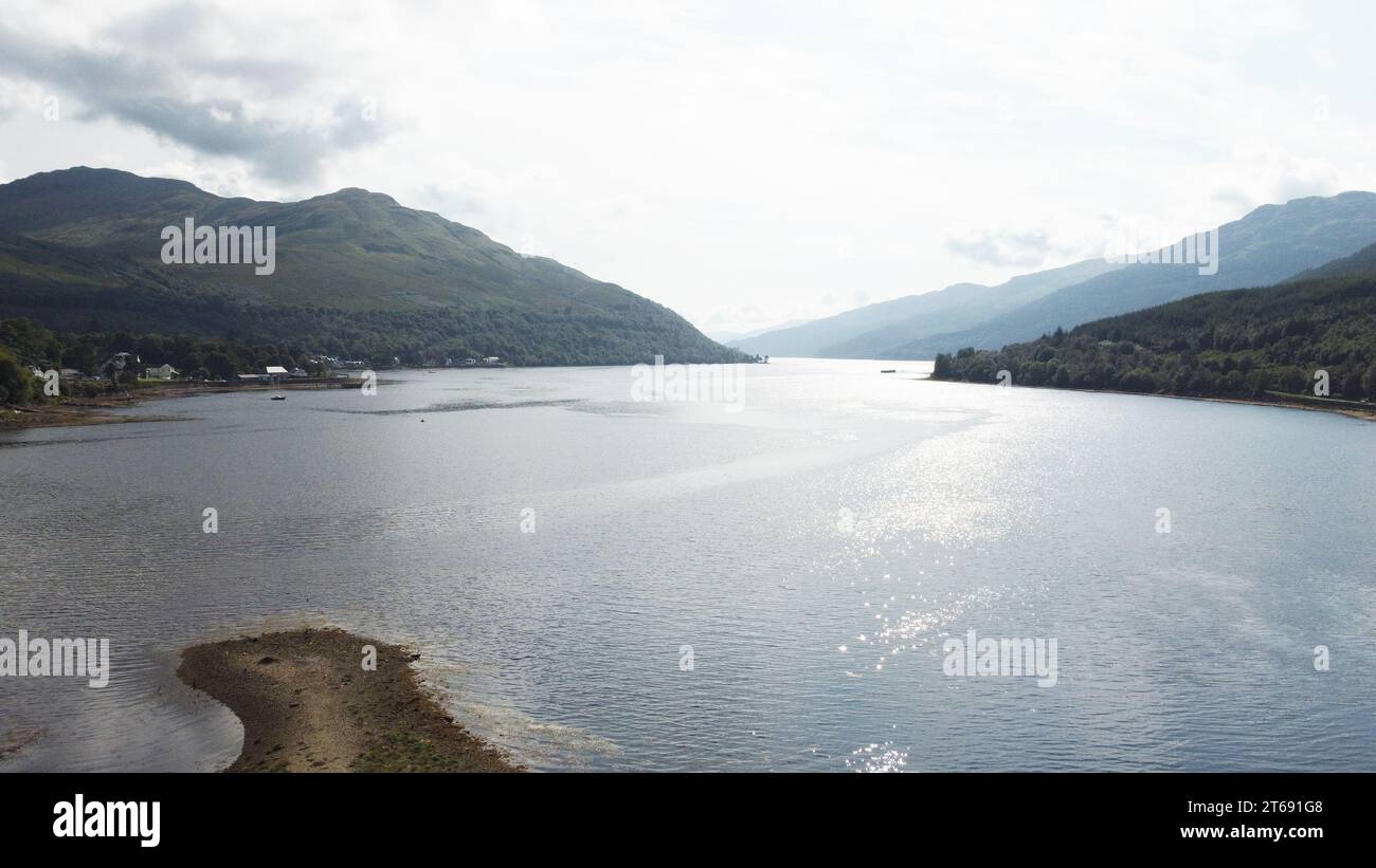 Vue aérienne d'un lac tranquille entouré de montagnes verdoyantes en arrière-plan, soulignant la beauté naturelle du paysage Banque D'Images