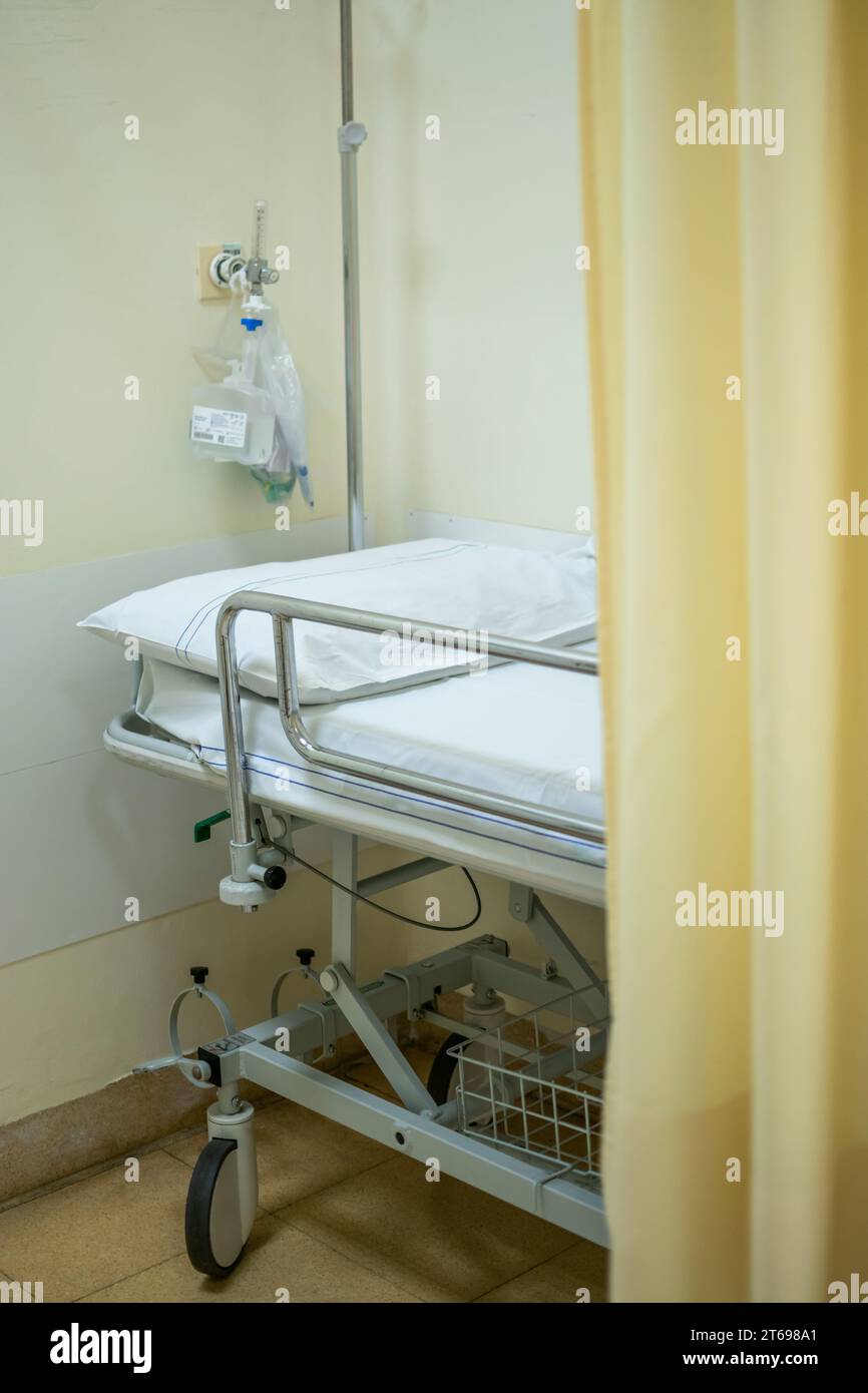Lit d'hôpital ou civière avec rideau jaune clair et oxygène purifié derrière Banque D'Images