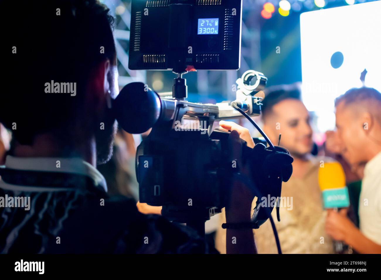Cameraman enregistrant un journaliste de télévision pendant une interview lors d'un événement en direct la nuit Banque D'Images