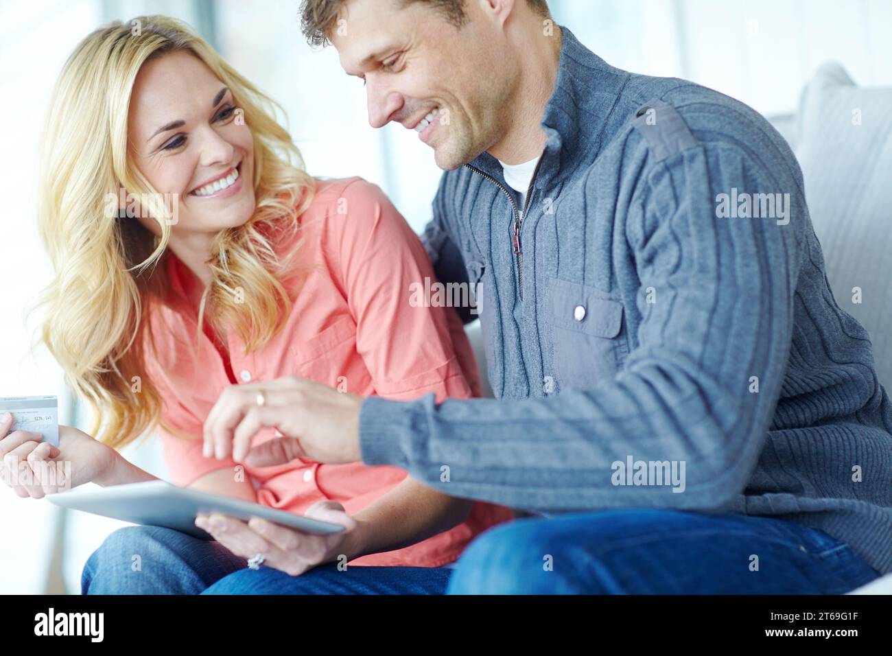 Shopping dans le confort de la maison. un heureux couple mature magasinant en ligne à l'aide d'une tablette numérique tout en se relaxant ensemble à la maison. Banque D'Images