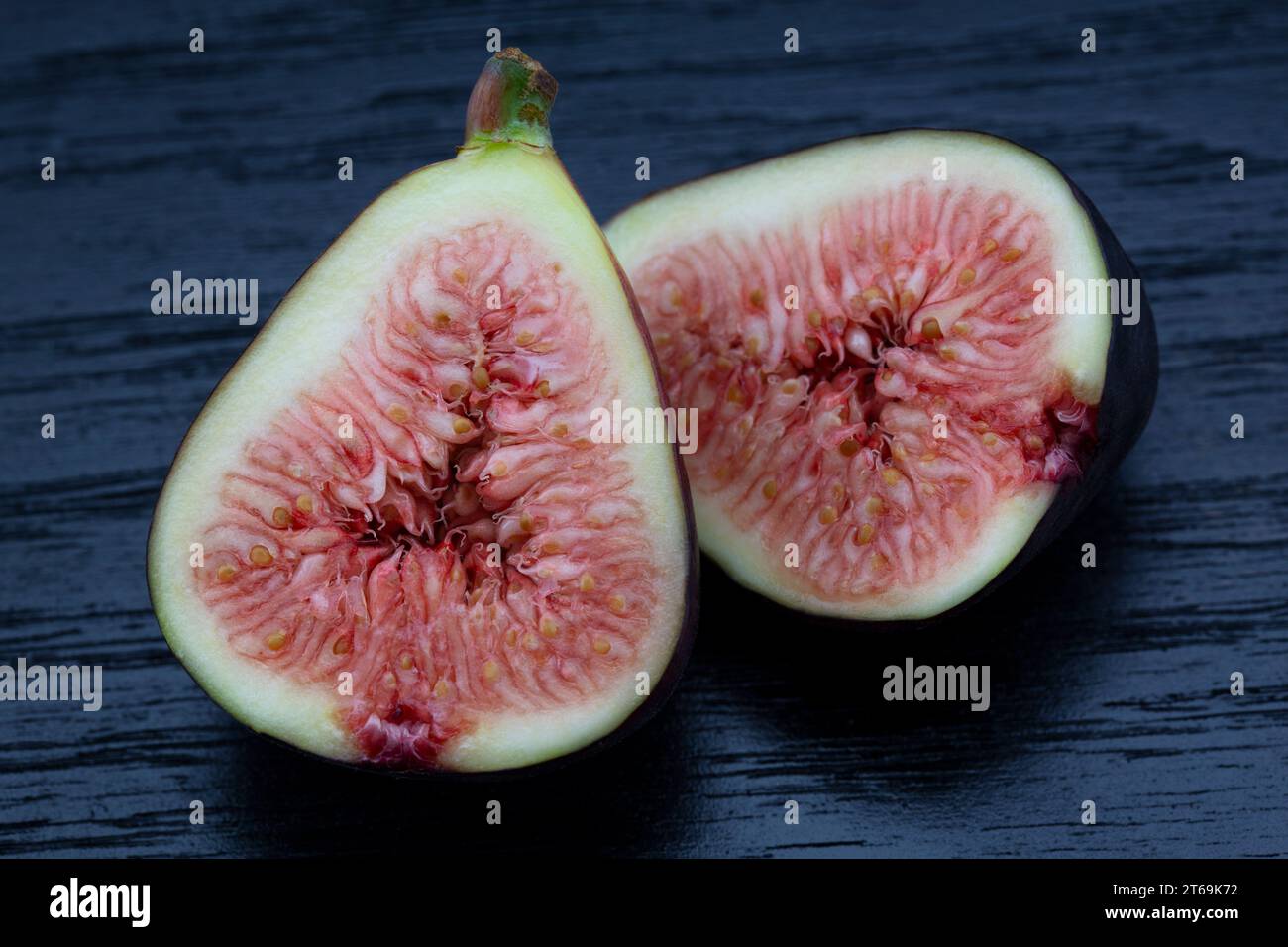 Vue macro des moitiés de figue dans la nature morte sur fond de planche de grain de bois montre la chair intérieure de ce fruit sain, spécialité Banque D'Images