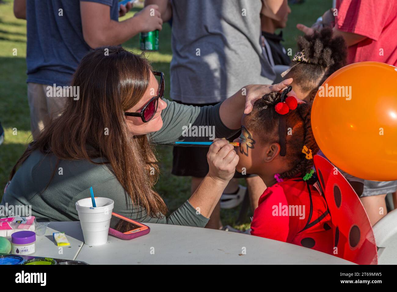 Femme peignant le visage d'un enfant pendant le festival d'automne à Crosspoint Church à Gulfport, Mississippi Banque D'Images