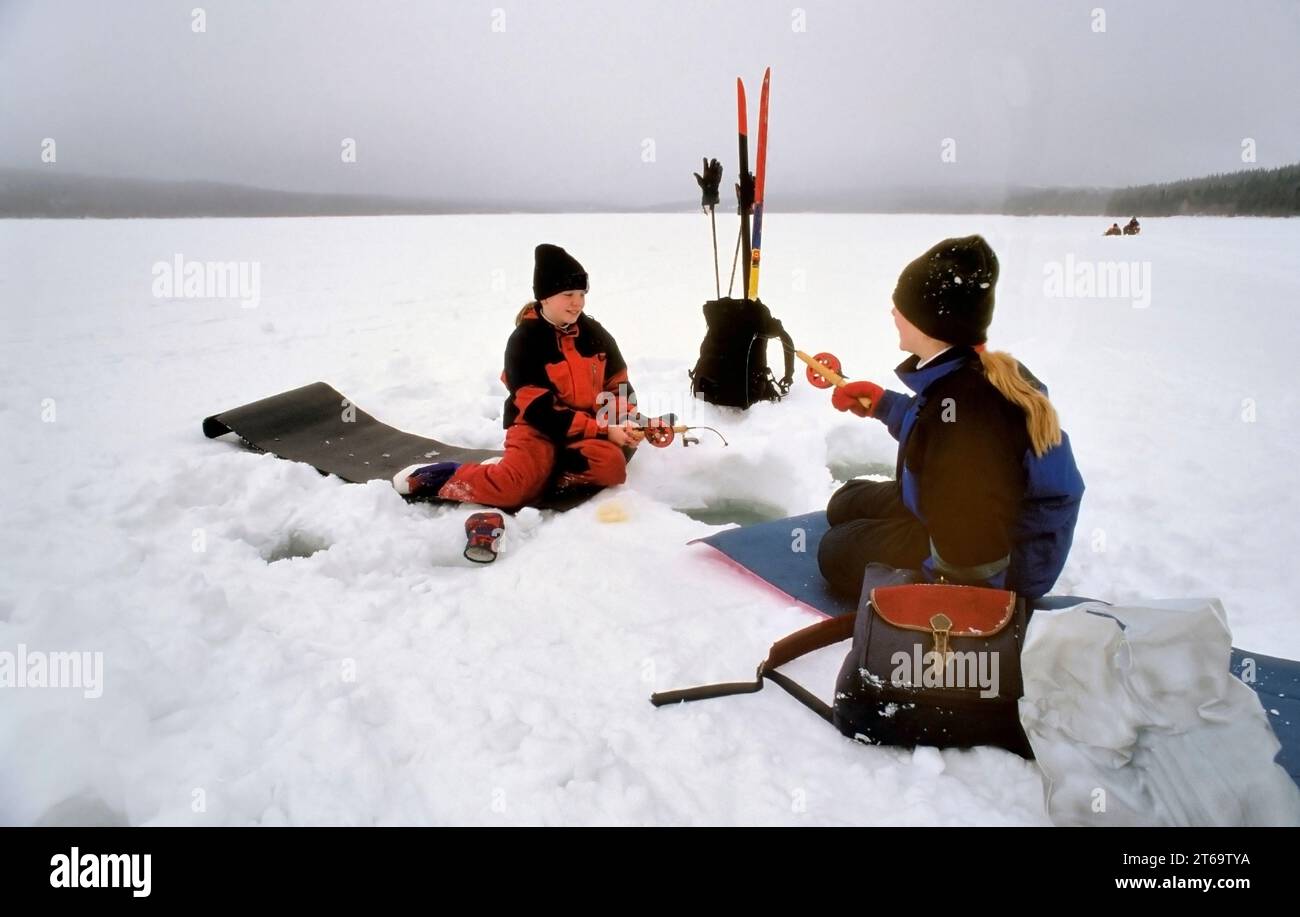 TROMSO, NORVÈGE - JANVIER 14 2022 : pêcheurs pêchant sur glace sur un lac gelé en hiver avec canne à pêche ou canne à pêche, tarière à glace et équipement pour la pêche Banque D'Images