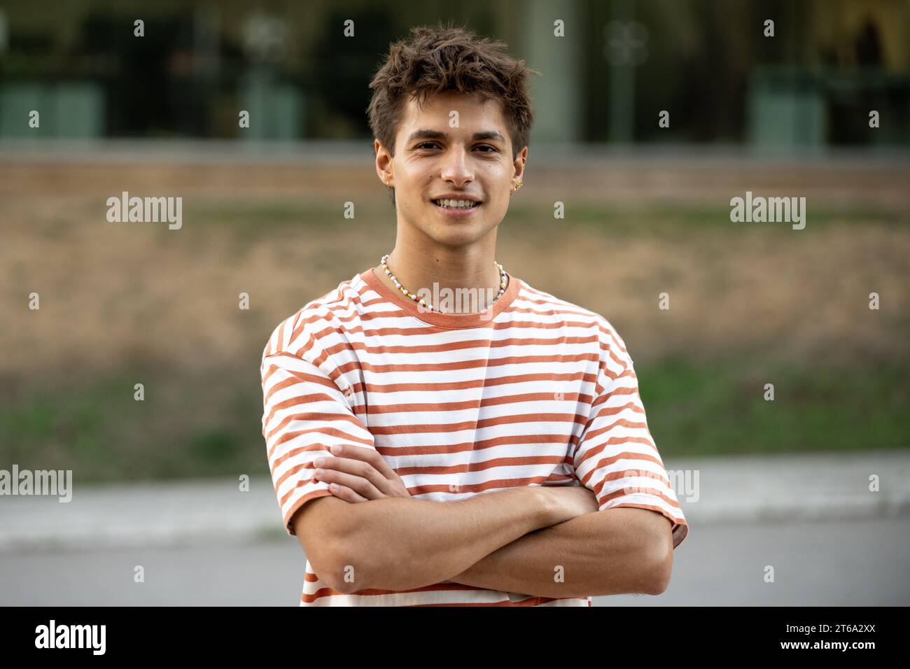 Jeune gars confiant regardant la caméra avec les bras croisés.adolescent satisfait debout détendu dehors et souriant. Banque D'Images