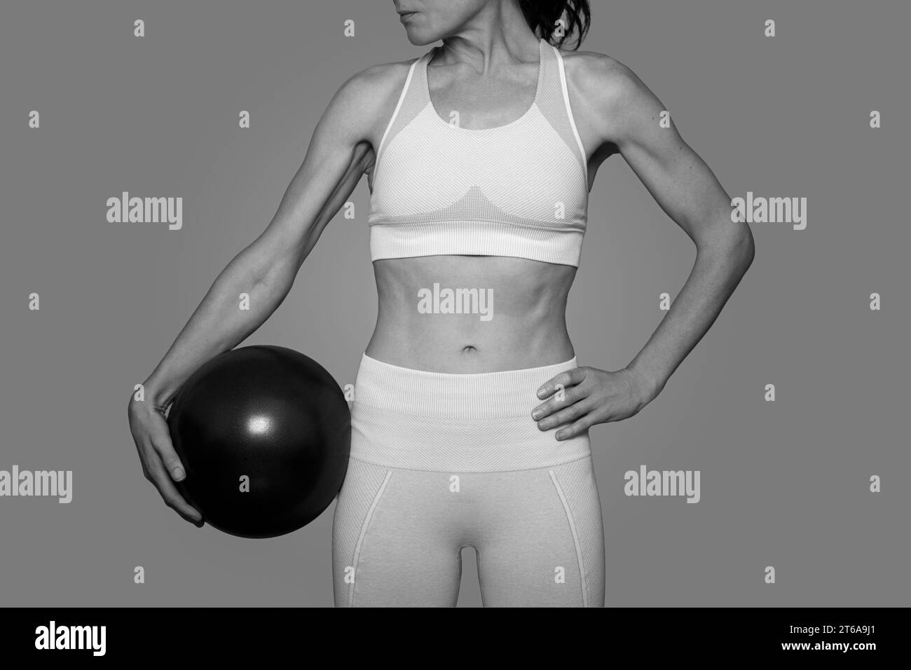 Femme en forme debout tenant une balle de pilates, noir et blanc. Banque D'Images
