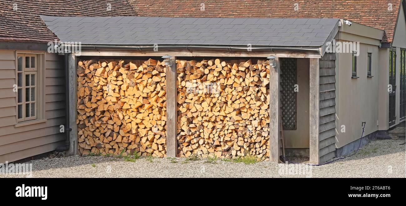 Structure allégée à abritée et protection du toit en pente pour couper les grumes de bois stockées à l'extérieur en hiver alimentent le feu ouvert intérieur dans la maison publique Essex Angleterre Royaume-Uni Banque D'Images
