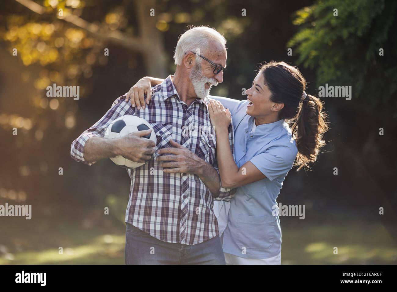 Homme senior et jeune femme infirmière jouant avec la balle dans le parc Banque D'Images