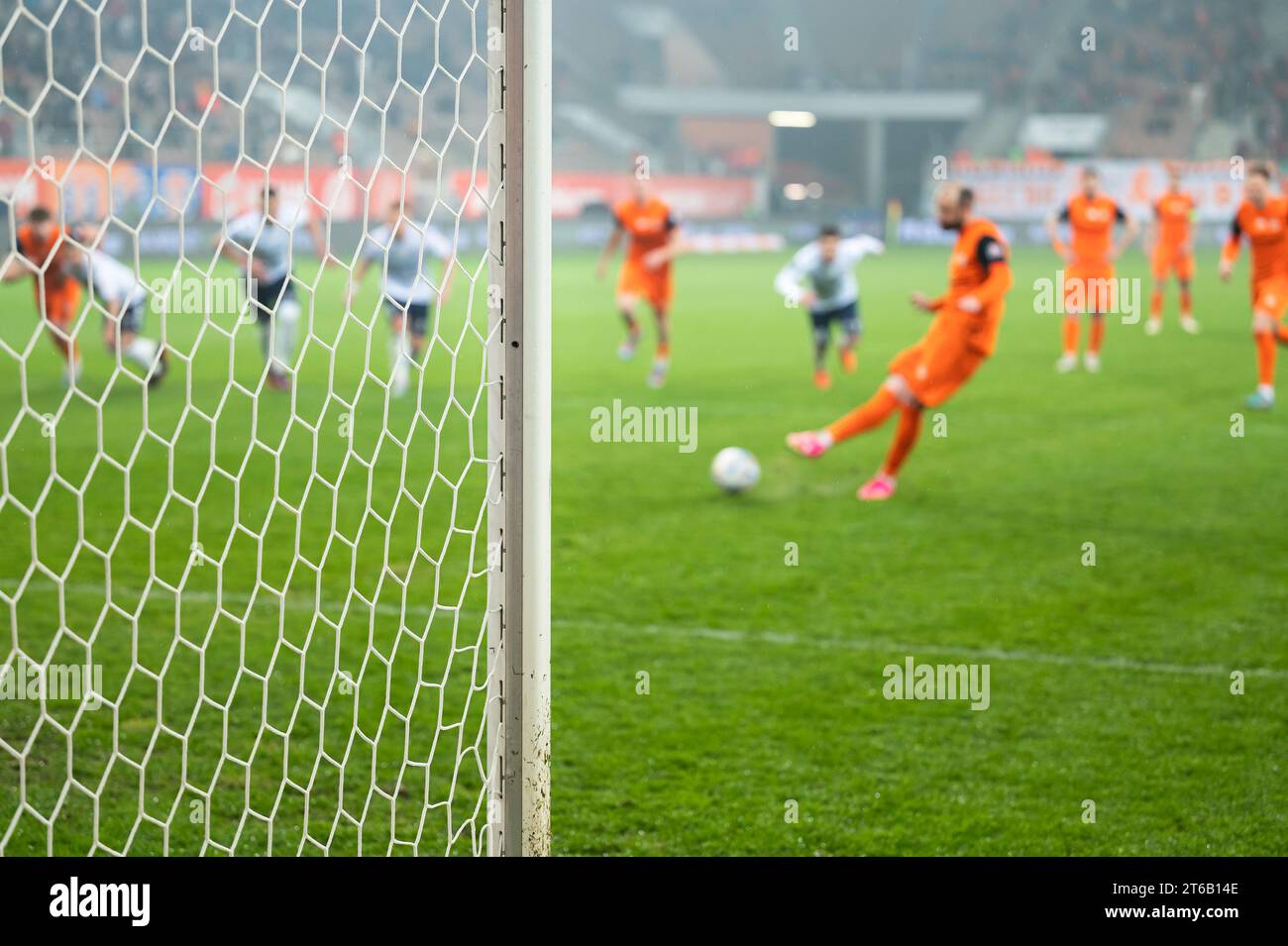 Détail du poteau de but avec le filet et le joueur de football pendant le coup de pied en arrière-plan. Banque D'Images