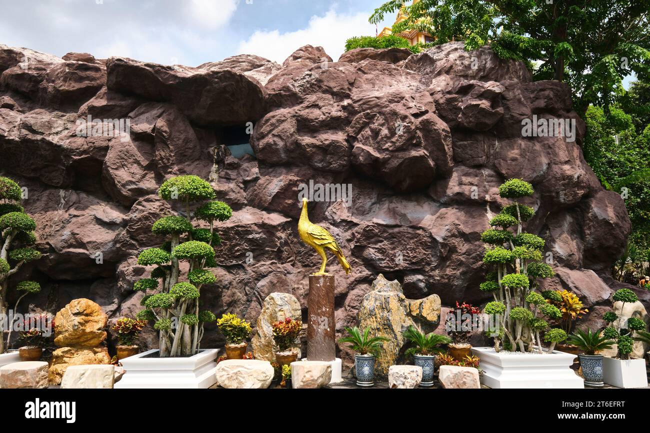 Une grotte rocheuse paysagée avec une statue en or d'un paon. Au Wat Saket, le Mont d'Or. À Bangkok, Thaïlande. Banque D'Images