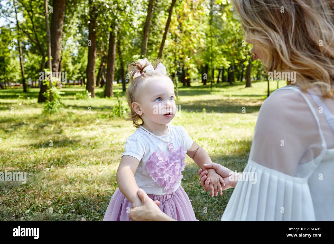 Mère et fille marchent dans le parc de la ville d'été. Enfance, loisirs et concept de personnes - famille heureuse repose sur la nature et passe un bon moment Banque D'Images