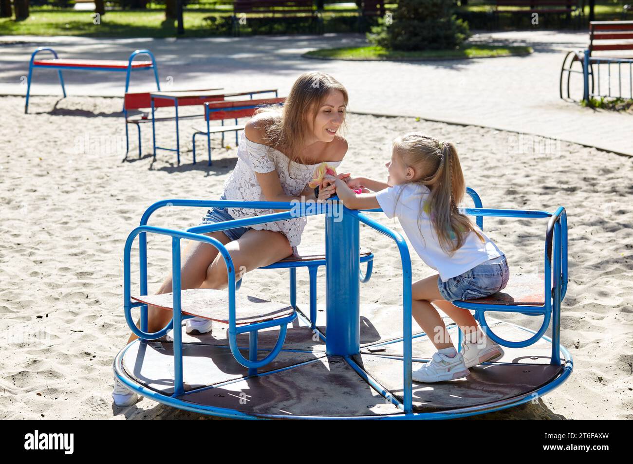 Mère et fille jouent sur l'aire de jeux dans le parc de la ville d'été. Enfance, loisirs et concept de personnes - repos familial heureux et passer un bon moment Banque D'Images