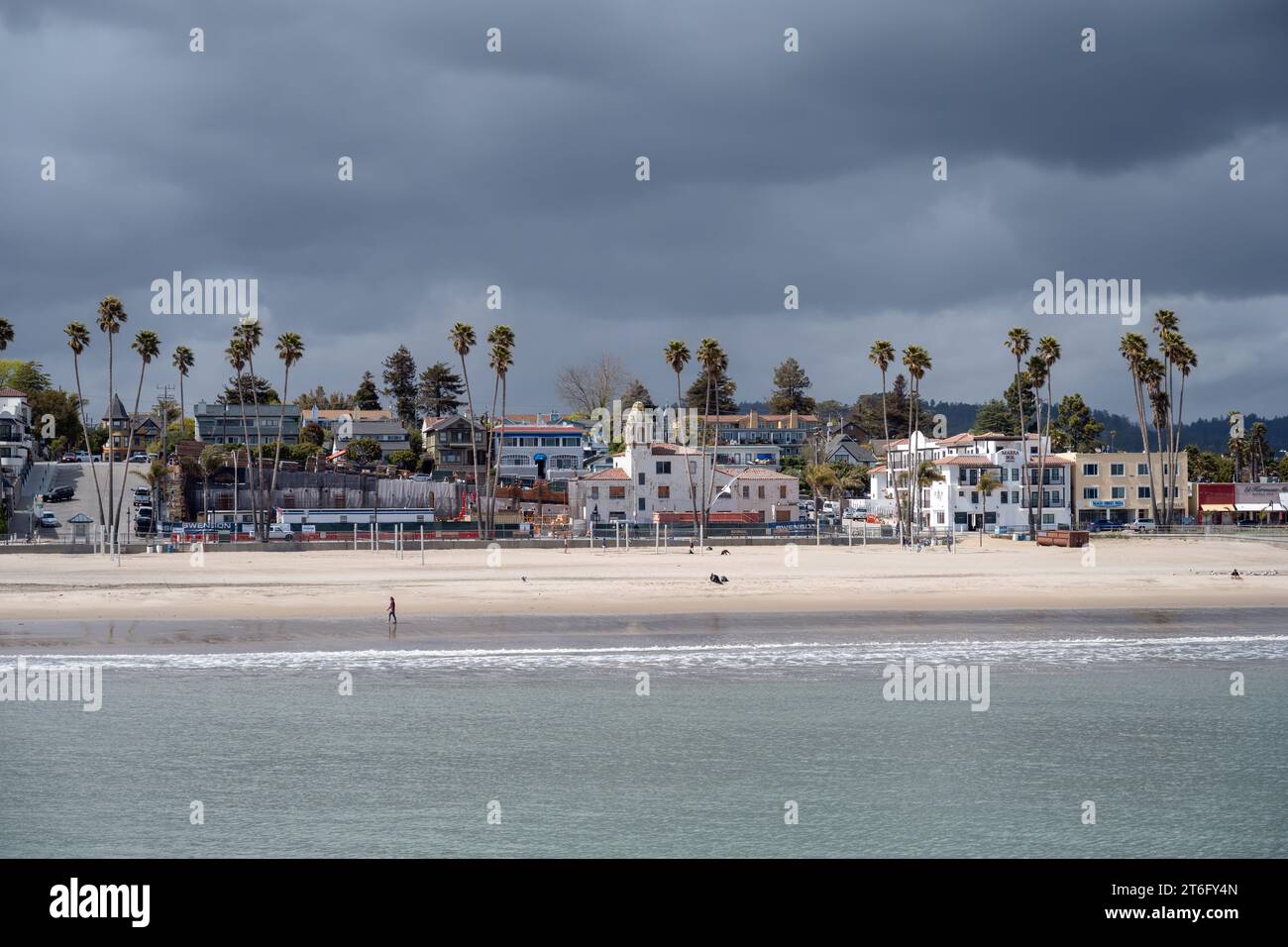 Santa Cruz, États-Unis - 05,02,2023 : Maisons situées parmi les palmiers tropicaux sur la plage de sable près de la mer ondulante sous un ciel nuageux orageux Banque D'Images
