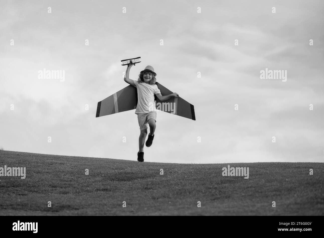 Aviateur de pilote d'enfant avec des ailes en papier ou un avion jouet rêve de voyager en été dans la nature. Banque D'Images