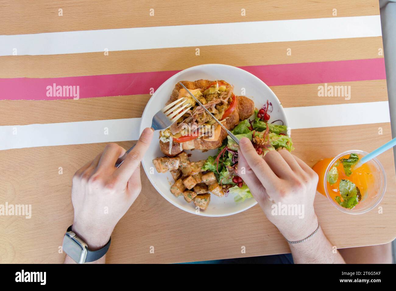 Personne ayant un sandwich au poulet croissant ouvert face avec des légumes sur le côté. Banque D'Images