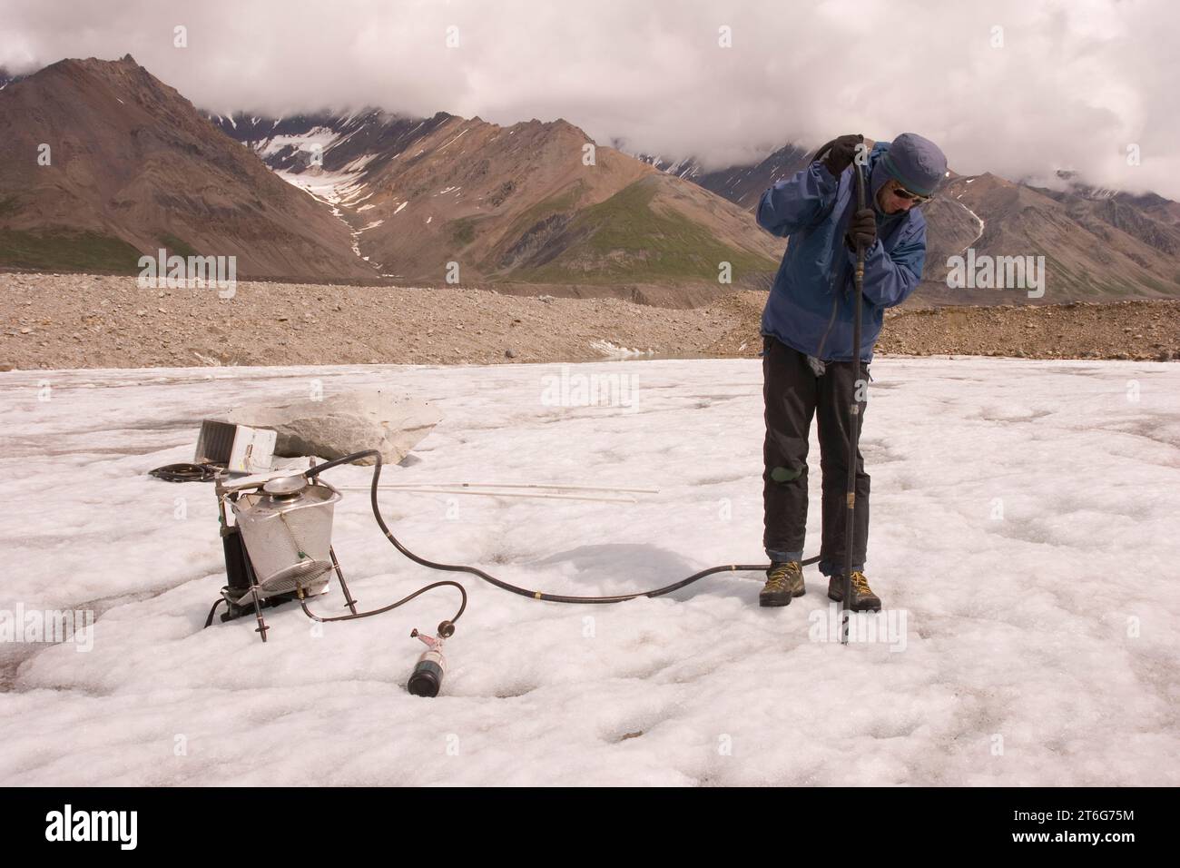Un glaciologue perce un trou pour installer de l'équipement sur le glacier Black Rapids, en Alaska. Banque D'Images Un glaciologue perce un trou pour installer de l'équipement sur le glacier Black Rapids, en Alaska. Banque D'Images