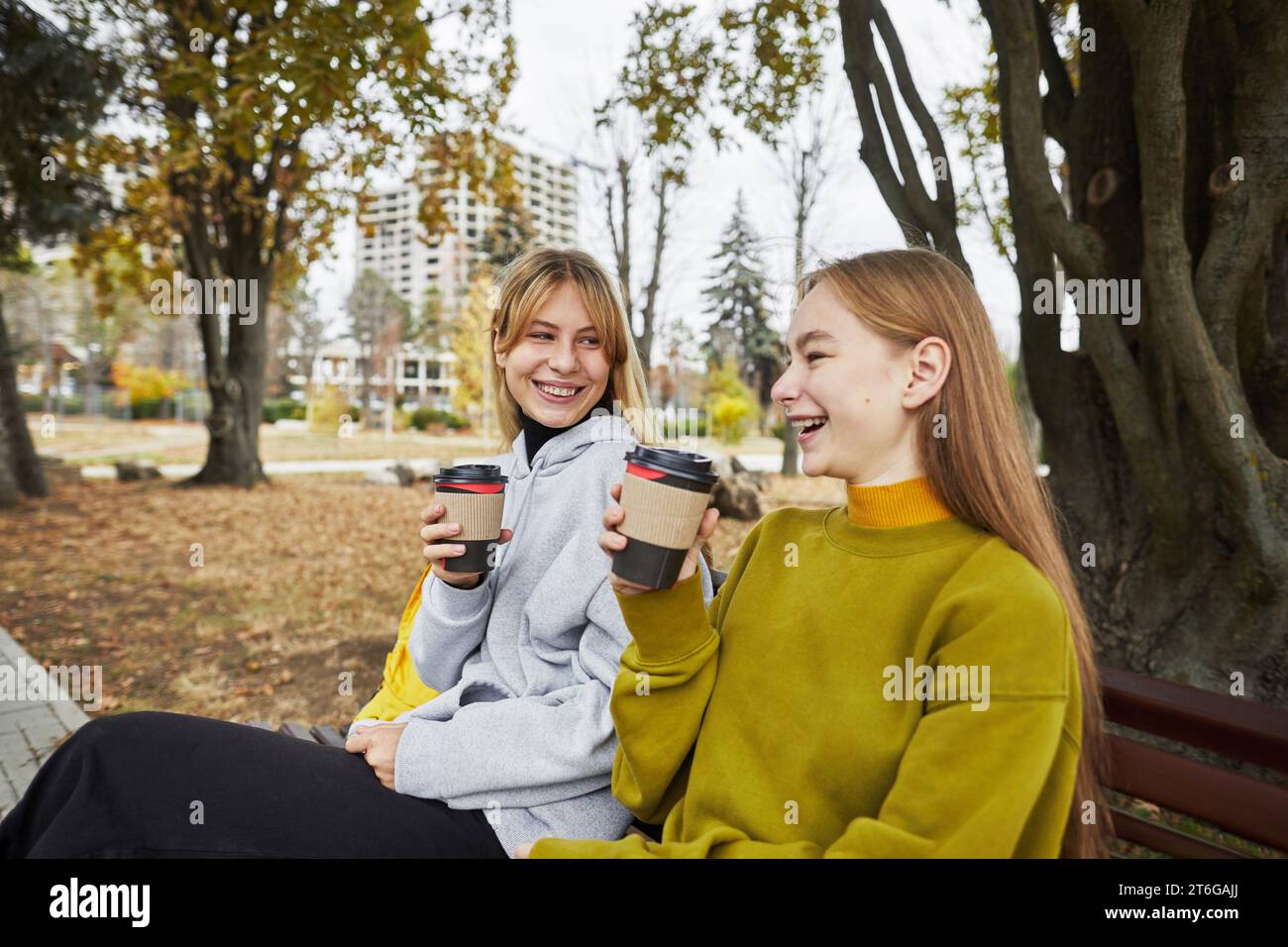 Deux jeunes femmes riantes avec des boissons dans le parc en automne Banque D'Images