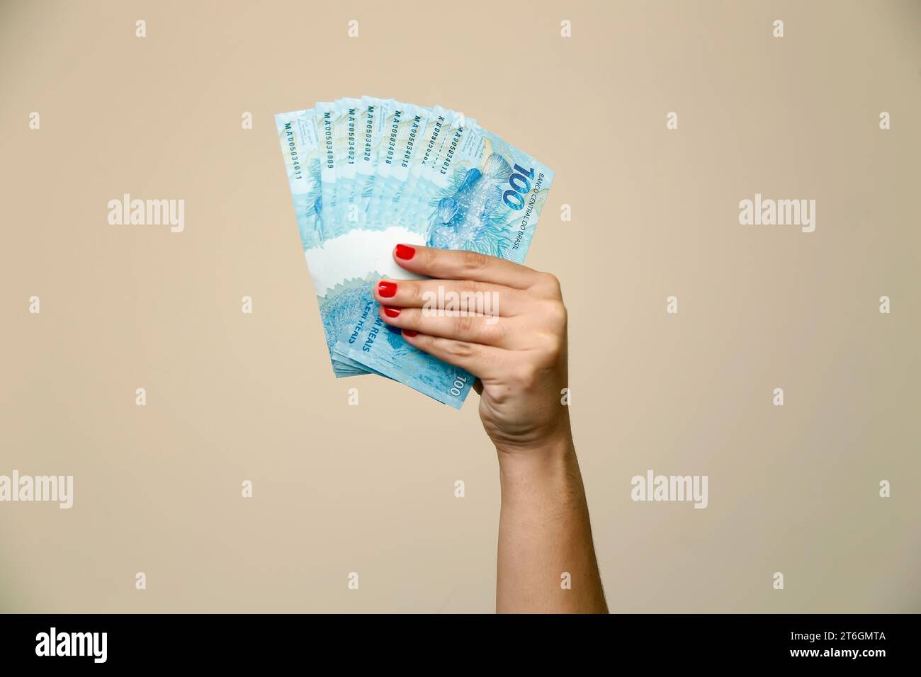 Plusieurs centaines de billets réels - de l'argent du Brésil dans une main de femme avec des ongles rouges - dos de note Banque D'Images
