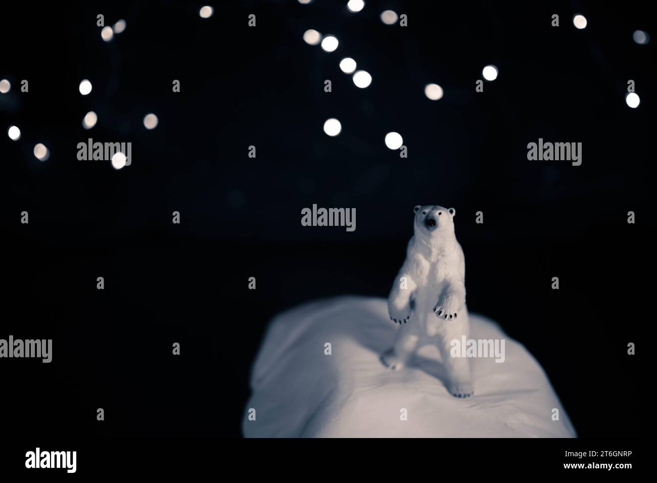 Figurine d'ours polaire debout à Noël ou le changement climatique, fond de nature morte de réchauffement climatique avec des lumières de chaîne et espace de copie. Banque D'Images