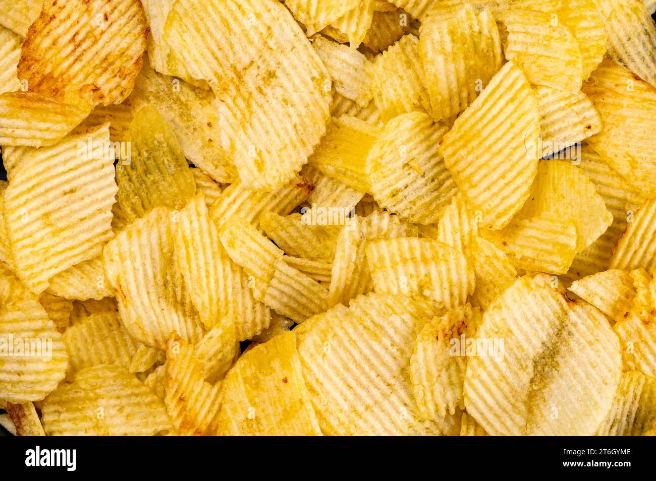 Vue de dessus des chips de pommes de terre ondulées frites et salées. Croustilles croustillantes délicieux en-cas d'apéritif sur le sol. Banque D'Images