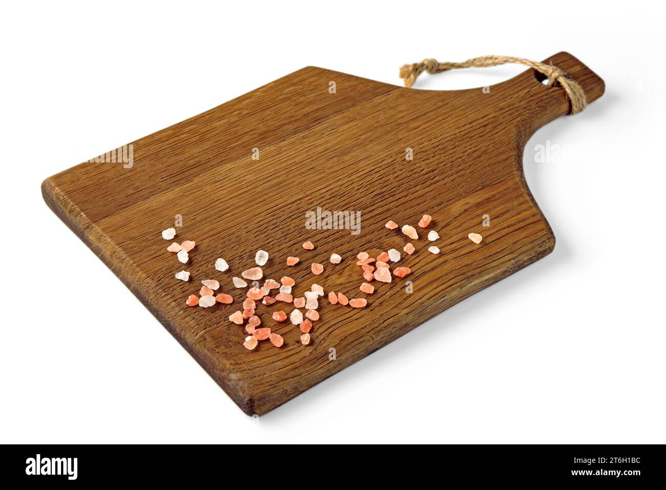 Planche à découper brun en bois avec du sel rose grossier dispersé isolé sur un fond blanc. Vue en grand angle Banque D'Images