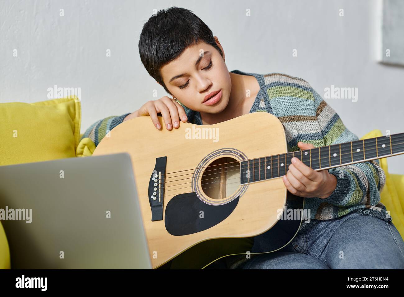 jeune femme concentrée apprenant à jouer de la guitare sur la leçon de musique à distance, l'éducation à la maison Banque D'Images
