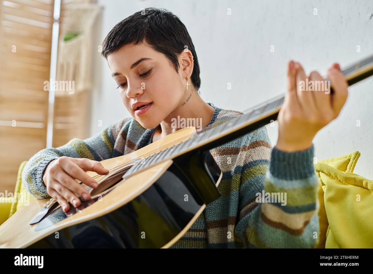 jeune femme concentrée en tenue décontractée jouant de la guitare sur la leçon de musique à distance, l'éducation à la maison Banque D'Images