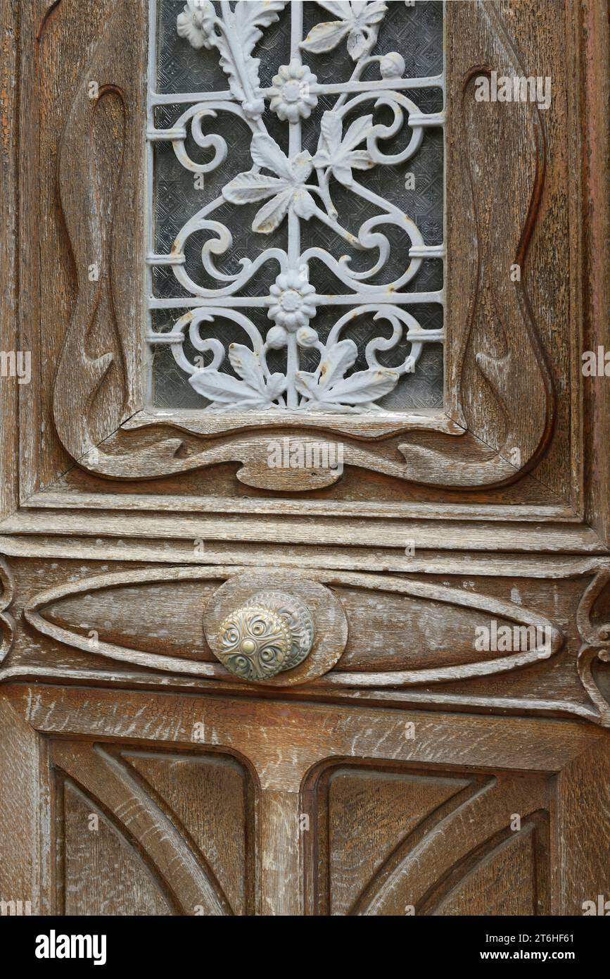 Vieille porte en bois avec bouton de porte en laiton orné et ferronnerie en fer forgé à motif floral peint recouvrant la fenêtre en verre, Honfleur, Calvados, Basse Normandie, Banque D'Images