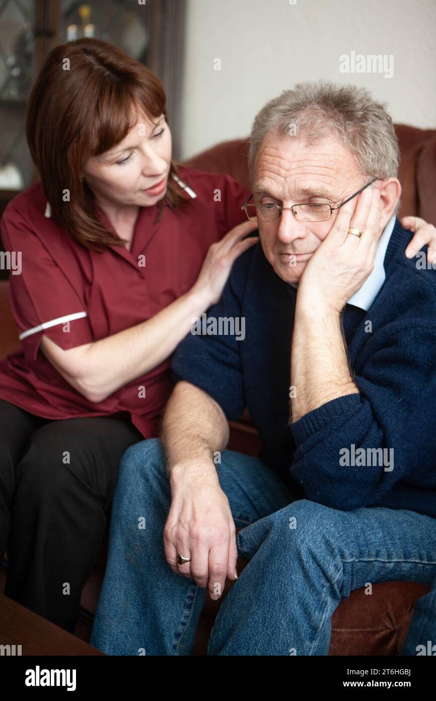 Aider les personnes âgées : le conseil en deuil. Un professionnel de la santé en visite prenant un moment pour consoler un homme âgé. À partir d'une série d'images associées. Banque D'Images