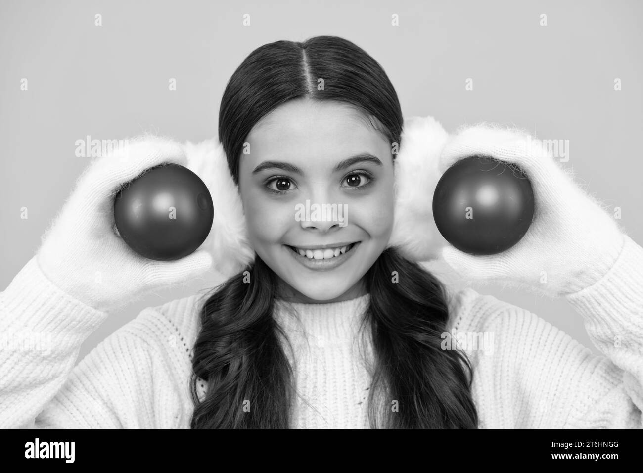 Joyeux noël et Bonne Année. Enfant en vêtements d'hiver. Jeune fille avec boule décorative. Visage heureux, émotions positives et souriantes de la jeune fille. Banque D'Images