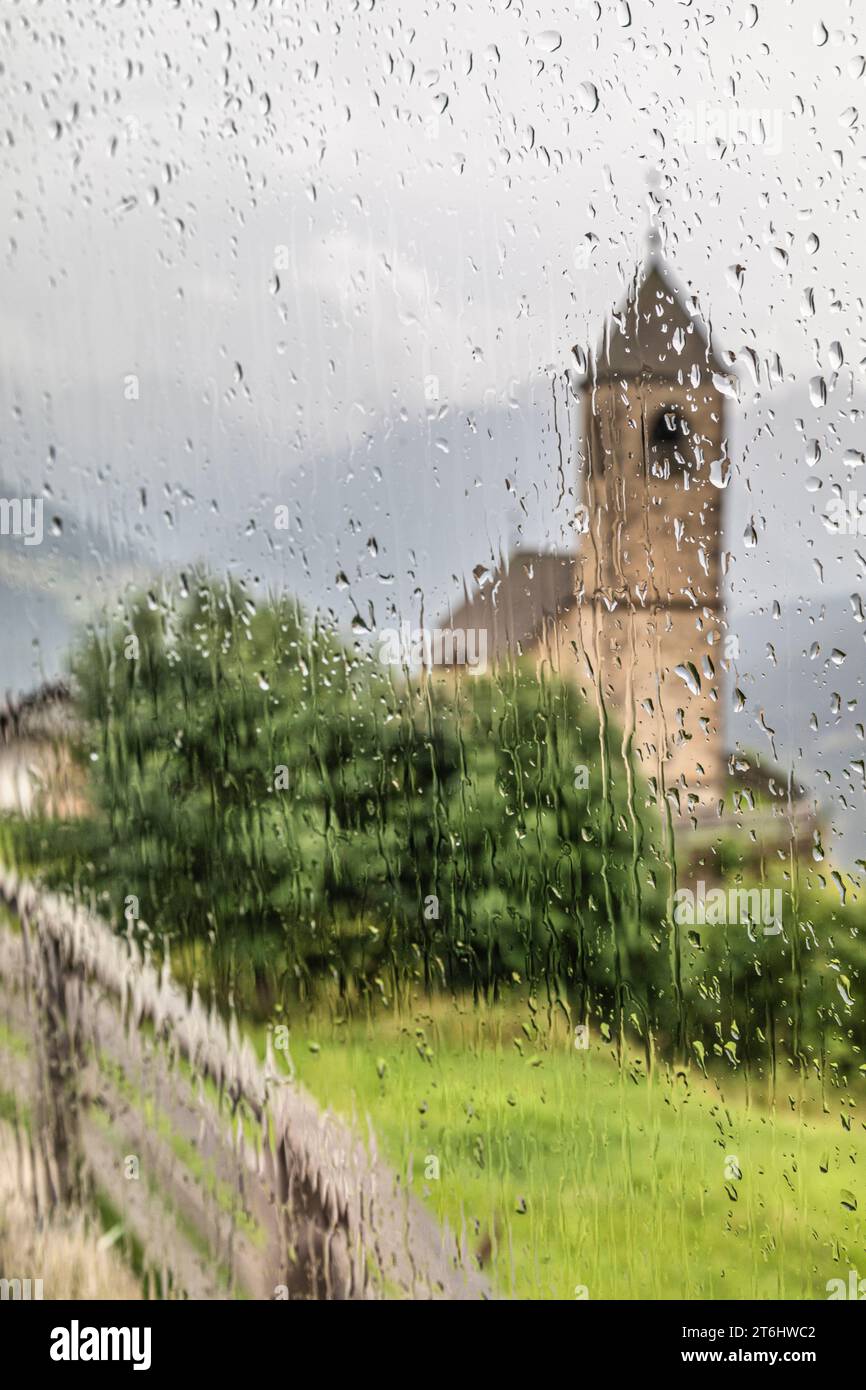 Italie, Vénétie, province de Belluno, Comelico Superiore, église de San Leonardo in Casamazzagno vu à travers une fenêtre mouillée de gouttes de pluie Banque D'Images