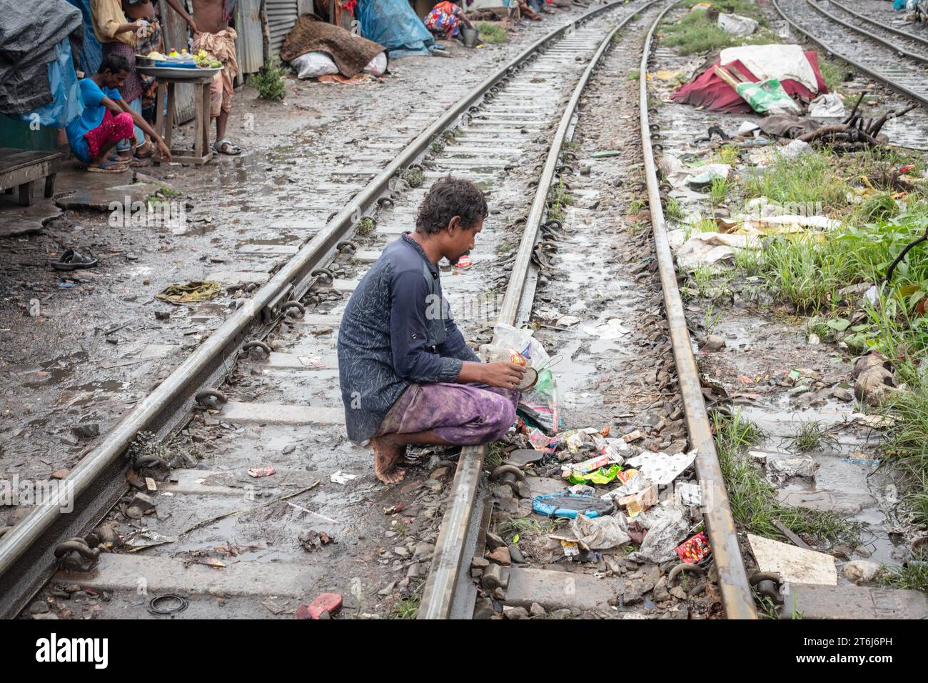 Un homme cherche les heures de repas entre les voies ferrées, Tejgaon bidonville, Dhaka, Bangladesh Banque D'Images