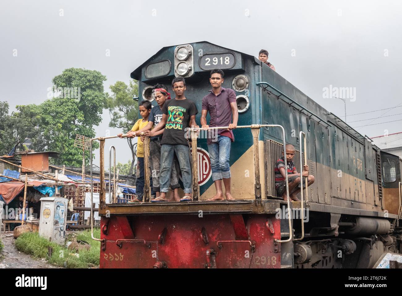 Enfants dans la locomotive d'un train traversant la colonie de Tejgaon construit le long de voies ferrées, dans le bidonville de Tejgaon, Dhaka (Bangladesh) Banque D'Images