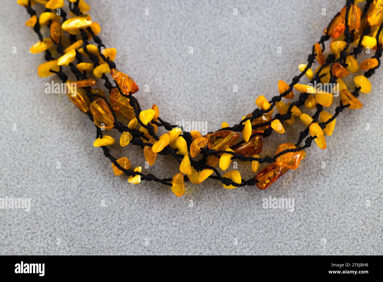 Un collier ambre poli élégamment enfilé sur un cordon noir. Les teintes brun doré de l'ambre Baltique créent une esthétique chaleureuse et naturelle. Banque D'Images