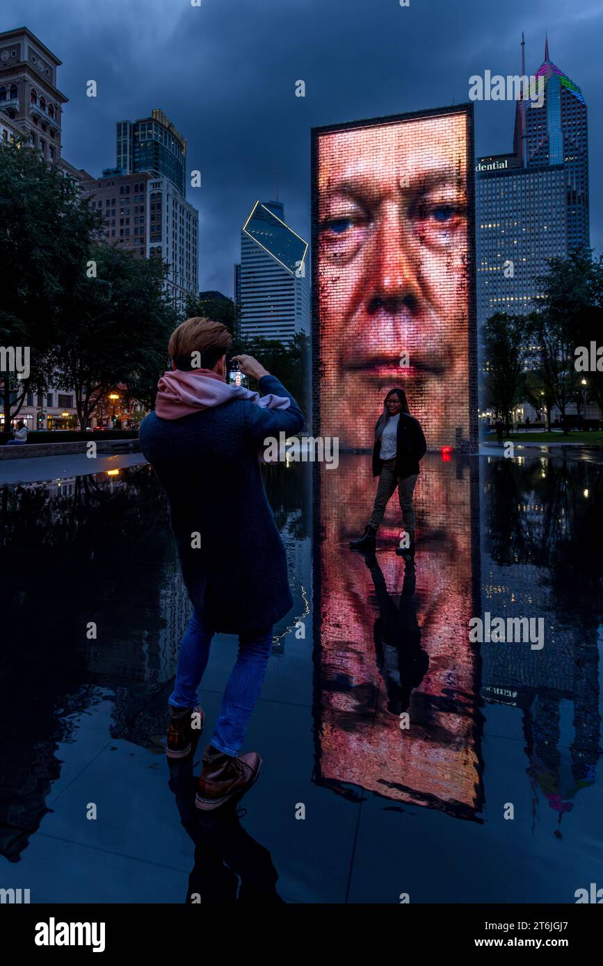 Les touristes prennent des photos de portrait devant l'installation artistique "visages de Chicago" dans le Millennium Park de Chicago, conçu par Jaume Plensa. La fontaine de la Couronne est une sculpture publique avec 2 50 pieds. Tours LED & une piscine réfléchissante, par l'artiste catalan Jaume Plensa à Chicago, États-Unis Banque D'Images