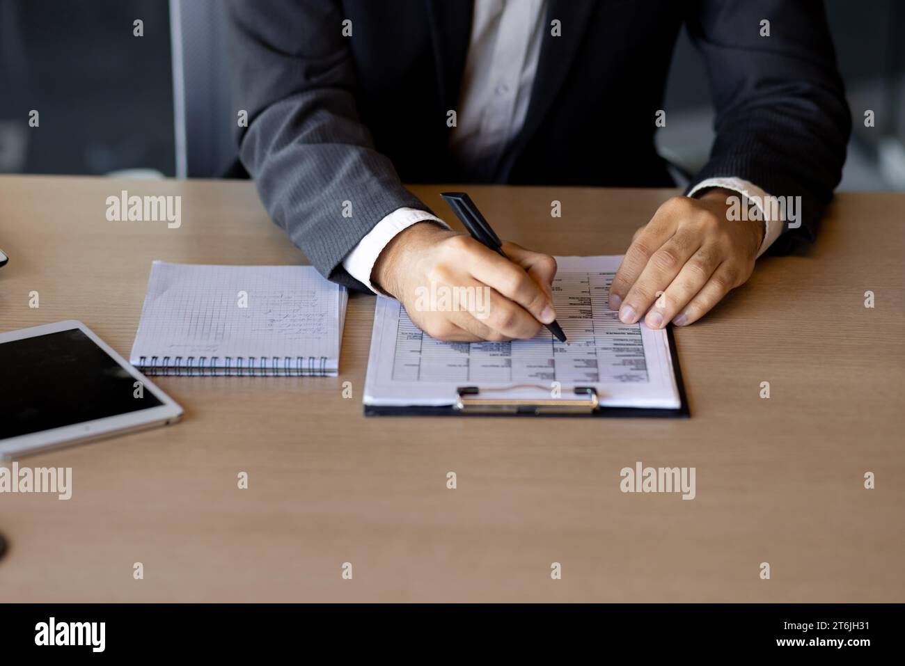 Homme d'affaires mains proches, homme remplit les tables à l'intérieur du bureau au lieu de travail, financier employé sur le travail de papier, utilise la calculatrice et l'ordinateur portable, mise au point sélectionnée. Banque D'Images