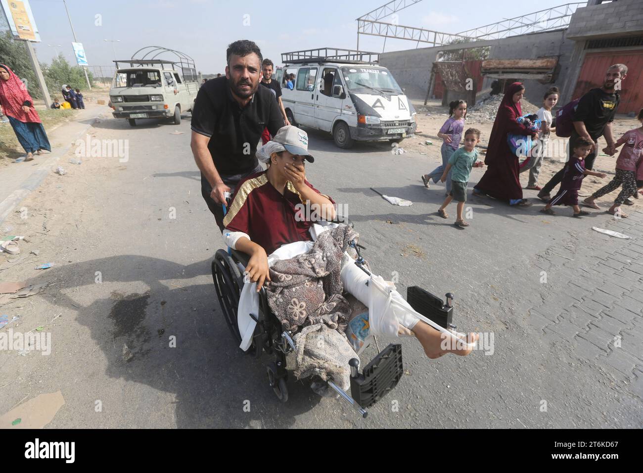 Un palestinien pousse sa femme blessée dans un fauteuil roulant alors que des familles palestiniennes fuient la ville de Gaza et d’autres parties du nord de Gaza vers les zones sud au milieu des combats en cours entre Israël et le mouvement palestinien Hamas. Des milliers de Palestiniens ont fui les violents combats entre les militants du Hamas et l’armée israélienne dans la ville de Gaza un mois après que le Hamas, basé dans la bande de Gaza, est entré dans le sud d’Israël le 7 octobre, dans une attaque sans précédent déclenchant une guerre déclarée par Israël au Hamas avec des bombardements de représailles sur Gaza. Banque D'Images