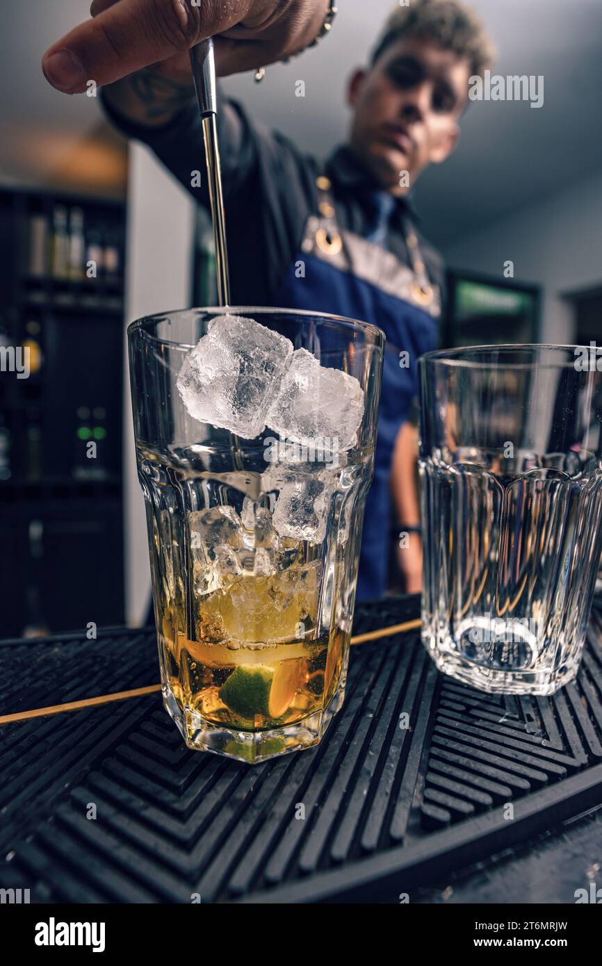 Cocktail alcoolisé sur le comptoir du bar, Bartender préparant un cocktail avec garnitures Banque D'Images