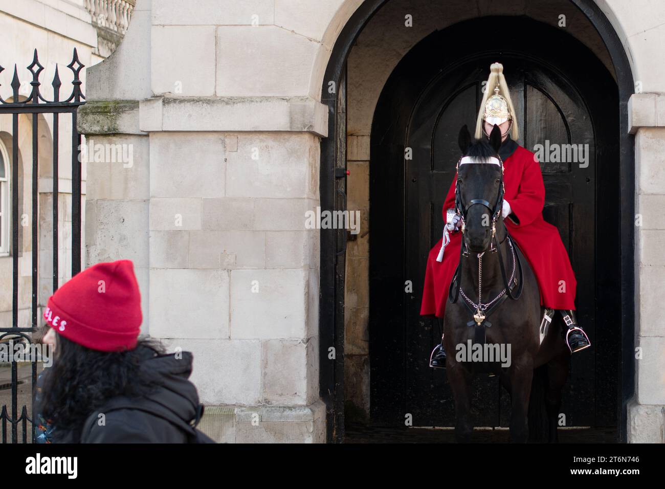 Image amusante d'un soldat du Household Cavalry Mounted Regiment avec l'oreille des chevaux obscurcissant partiellement son visage tandis qu'une personne passe devant Banque D'Images